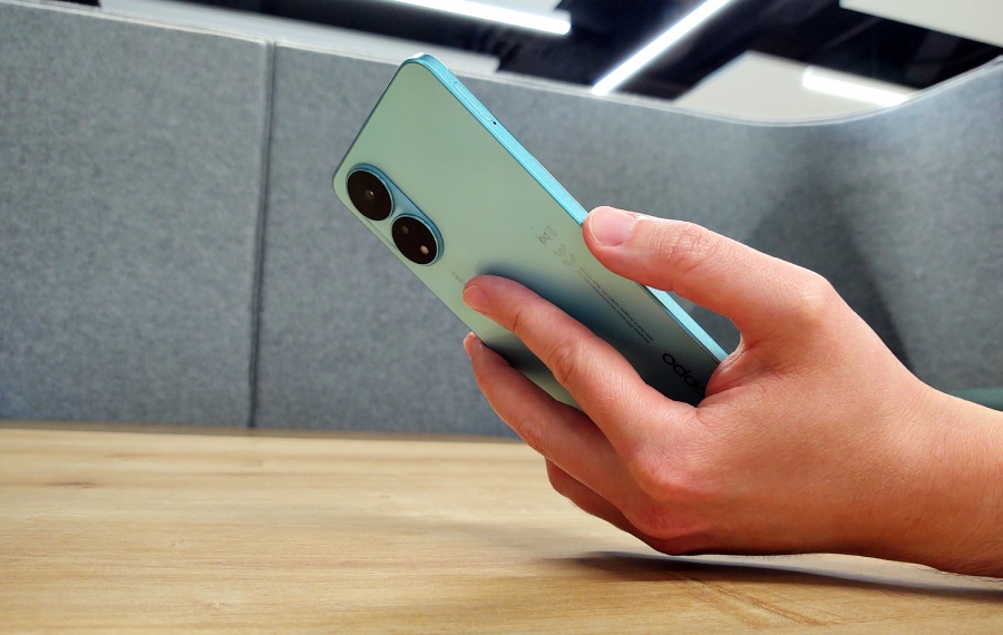 smartfon oppo A78 w ręce nad stolikiem z drewnianym blatem