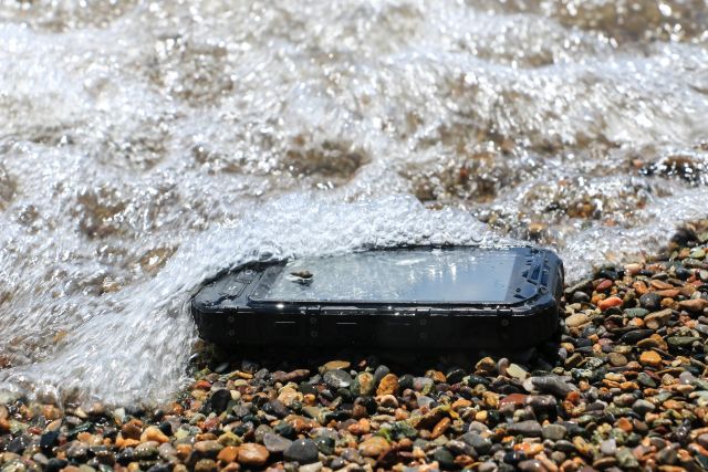 Smartfon znajdujący się na brzegu, zalewany przez wodę