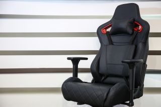 Czarne krzesło komputerowe z podstawka pod głowe i podpórka pod odcinek lędźwiowy kręgosłupa.