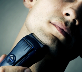 Mężczyzna goli się golarką elektryczną