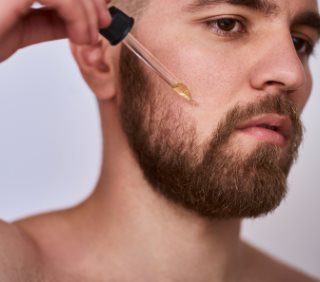 Mężczyzna nakłada olejek do pielęgnacji brody