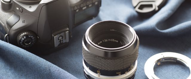 Stary obiektyw z manualnym autofocusem obok adaptera i aparatu