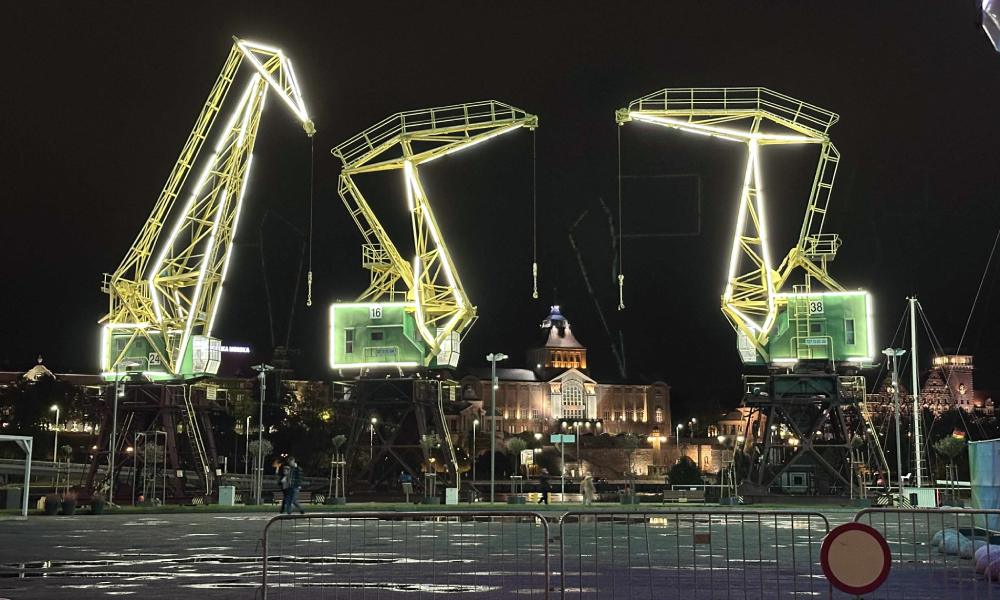 nocne zdjęcie podświetlonych trzech dźwigów portowych w Szczecinie