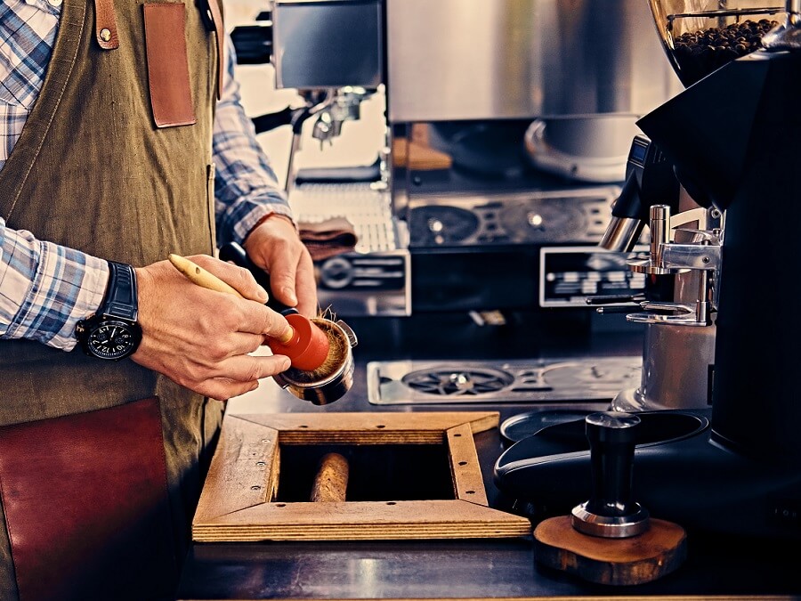 Mężczyzna czyści kolbę ekspresu kolbowego specjalnym pędzelkiem