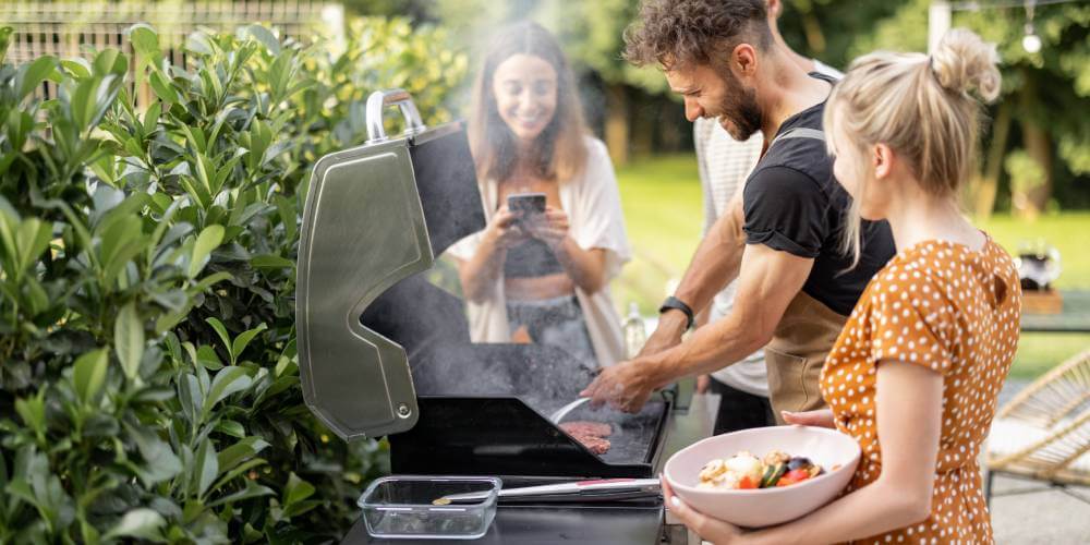 Zadowoleni ludzie spędzają czas przy grillu ogrodowym