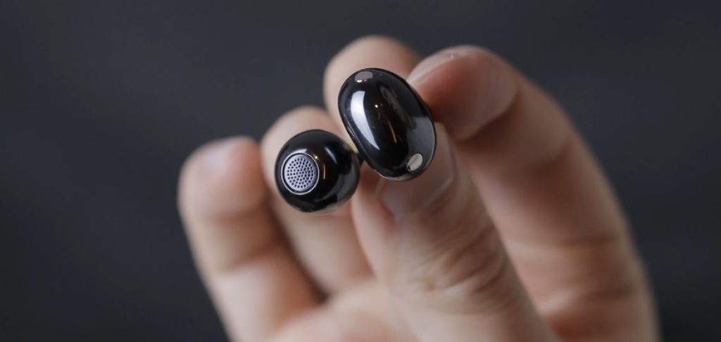 zbliżenie na czarną słuchawkę TWS trzymaną w dłoni