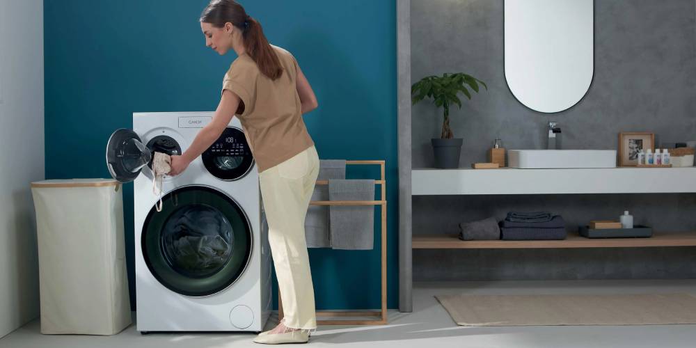 Młoda kobieta włącza nowoczesnę pralkę z trzema bębnami Candy MultiWash