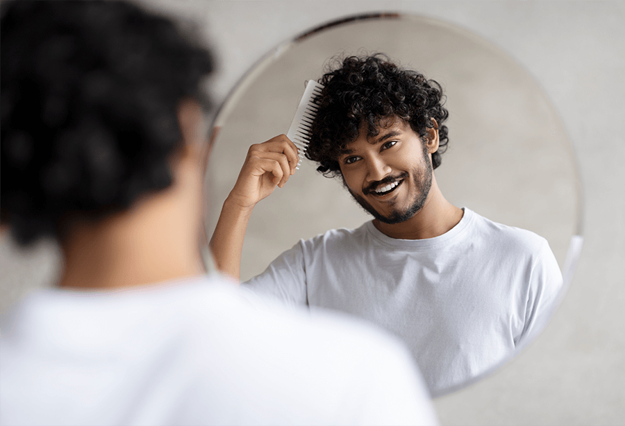 Mężczyzna z kręconymi włosami stoi przy lustrze