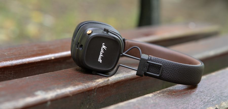 słuchawki Marshall Major IV leżą na ławce w parku