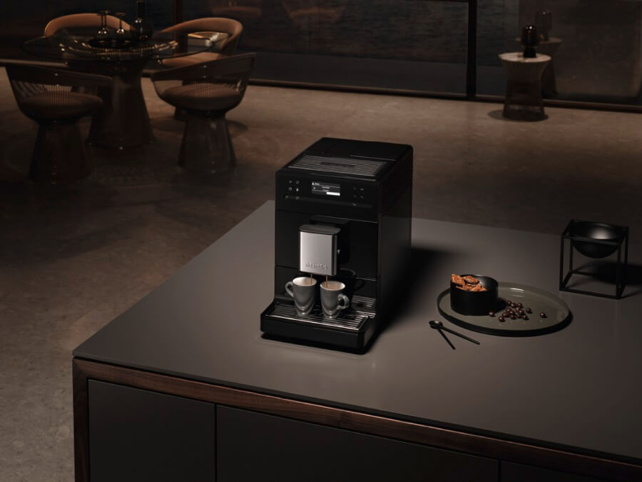 Automatyczny ekspres ciśnieniowy Miele, który stoi na wyspie kuchennej, przygotowuje właśnie dwie filiżanki espresso jednocześnie