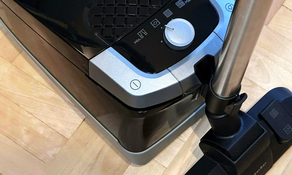 zbliżenie na przyciski i kółko sterujące czarnego odkurzacza Miele
