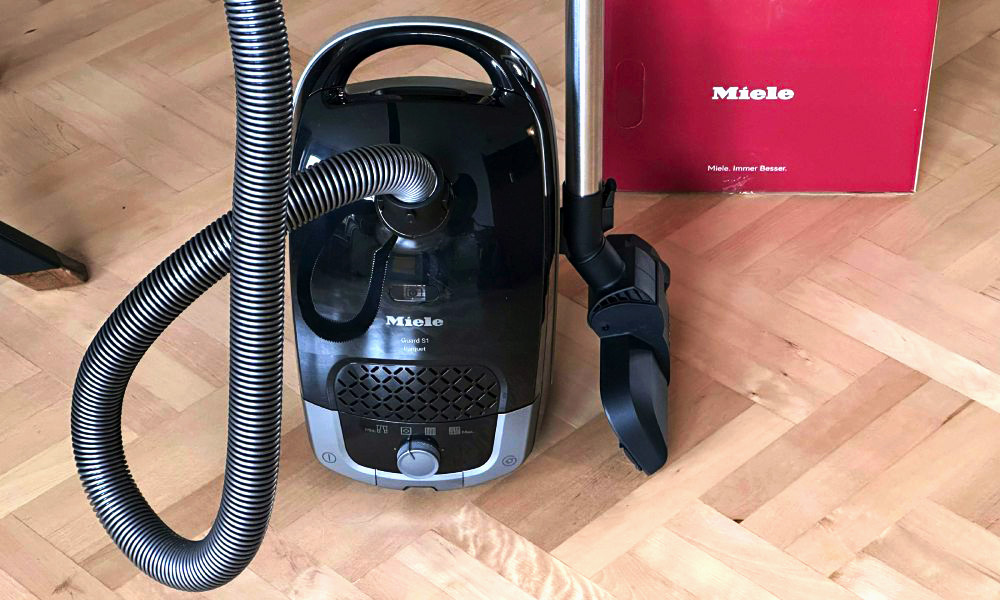 czarny odkurzacz Miele na parkietowej podłodze