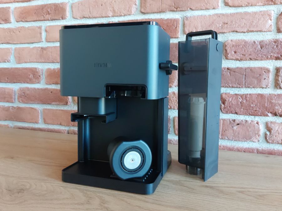 Ekspres Nivona Cube z kubkiem Click Cup i wyjętym zbiornikiem na wodę, kt&oacute;ry stoi obok urządzenia