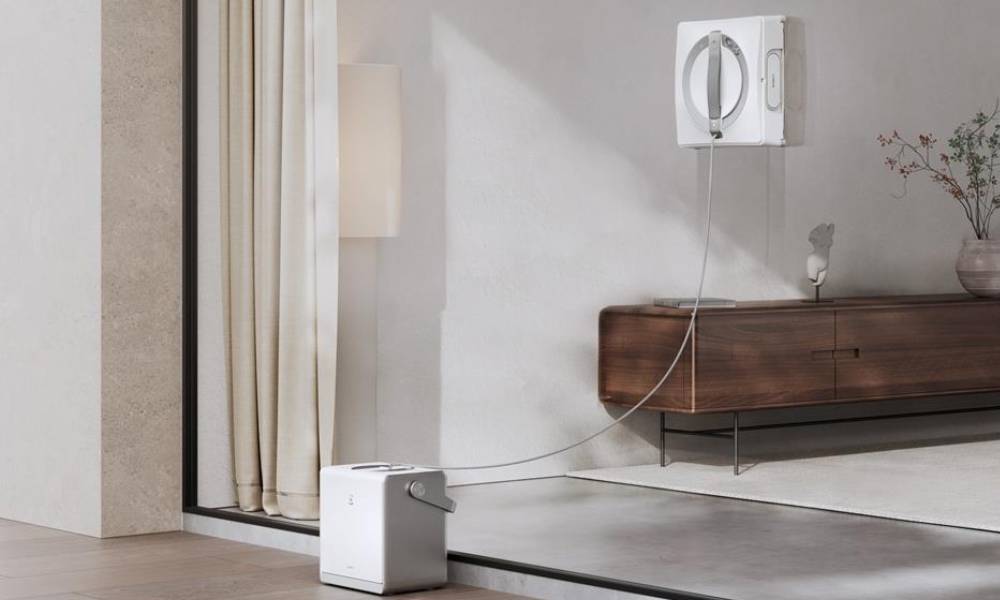 Robot do mycia okien pracuje na szybie podłączony do przenosnej stacji zasilającej