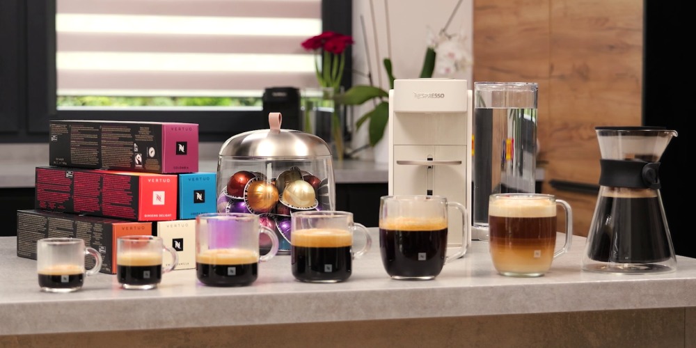 napoje kawowe w siedmiu r&oacute;żnych rozmiarach stojące przed ekspresem kapsułkowym Nespresso