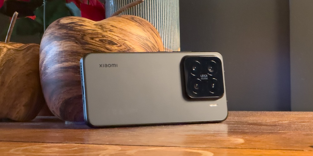 Smartfon Xiaomi 15 w czarnej wersji kolorystycznej oparty o drewniane jabłko