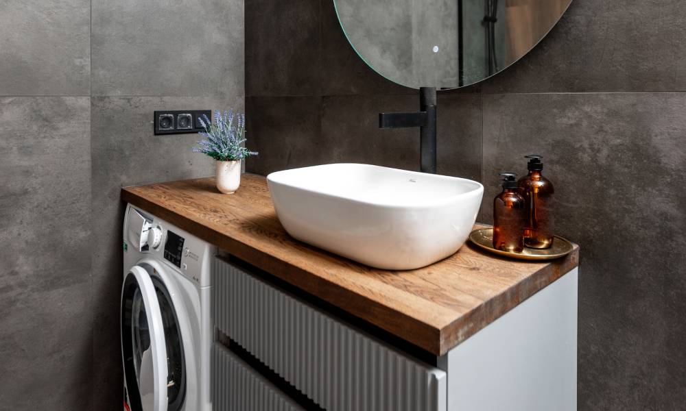 Pralka zabudowana w łazience pod blatem, na kt&oacute;rym ustawiona jest umywalka
