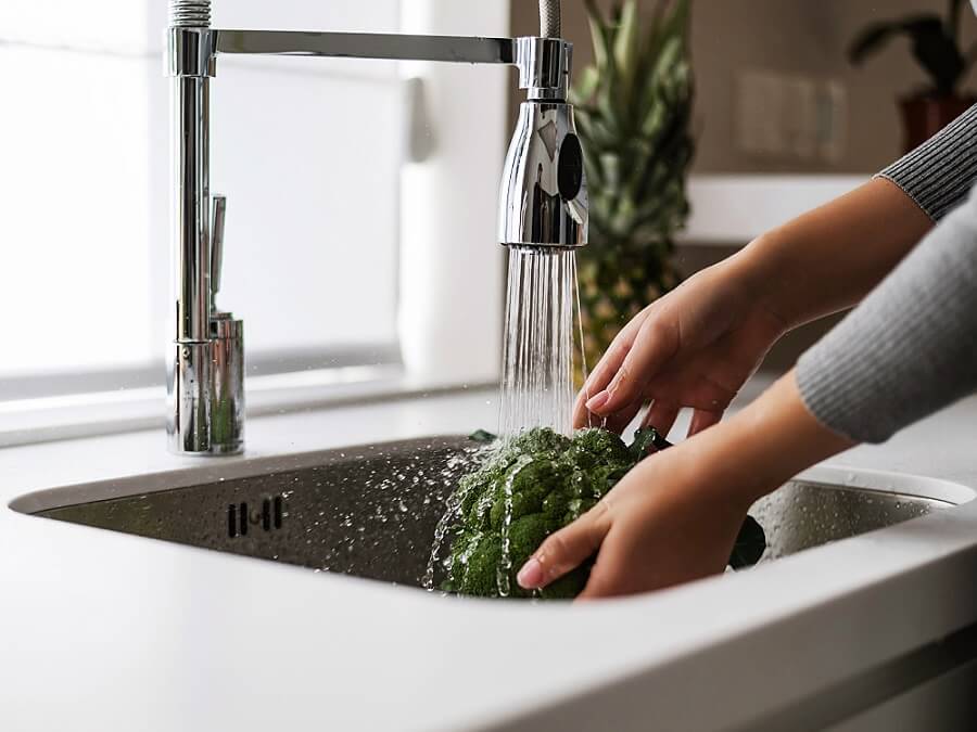 Kobiet myje brokuły w zlewozmywaky jednokomorowym, stalowym, podwieszanym