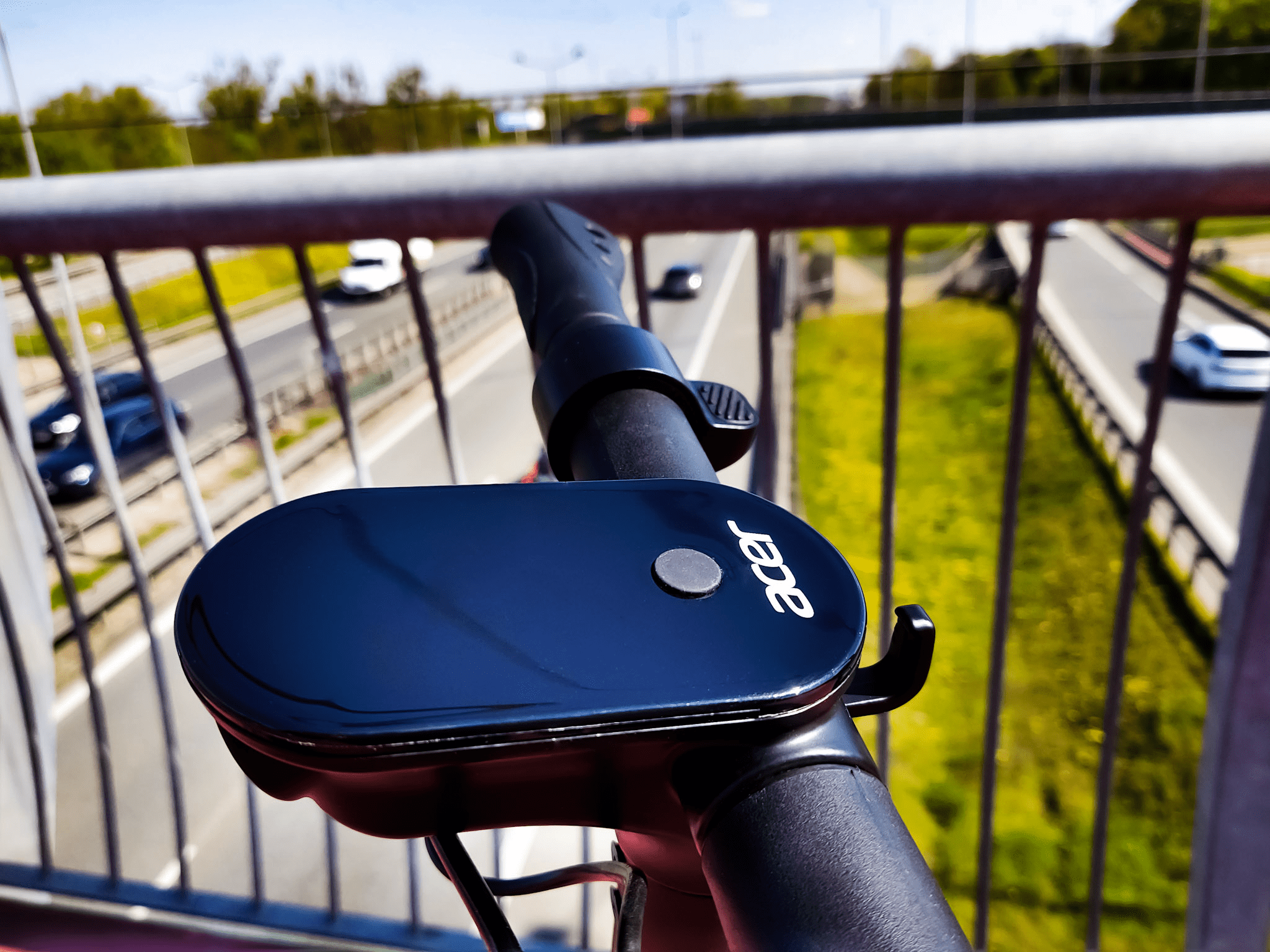 tym razem hulajnoga acer es series pozuje na kładce dla pieszych nad ruchliwą drogą. prezentuje sw&oacute;j minimalistyczny ekran.