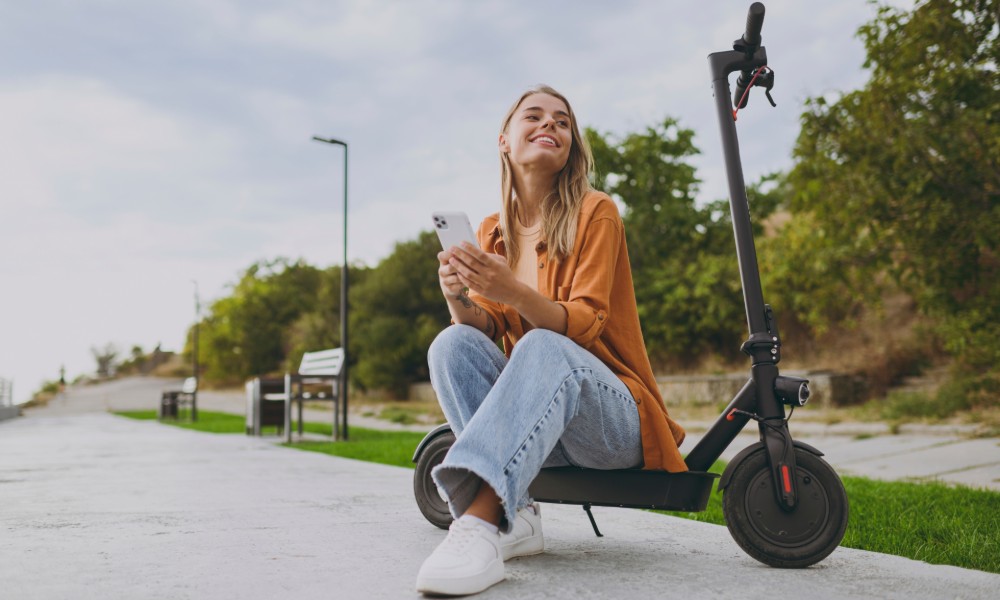 Kobieta siedząca na decku hulajnogi elektrycznej