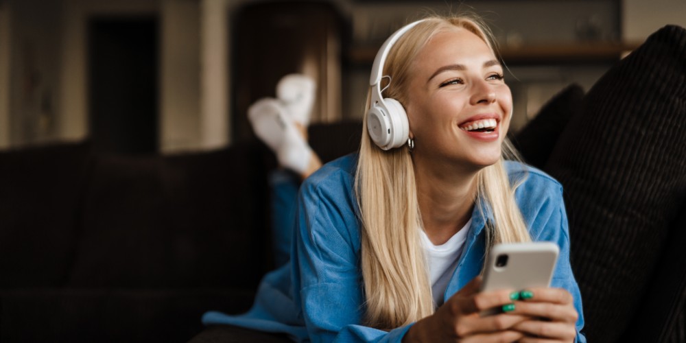 Kobieta w słuchawkach połączonych z telefonem