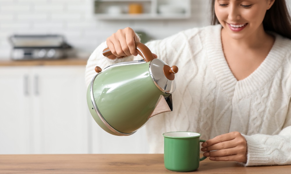 kobieta nalewa wodę z czajnika elektrycznego