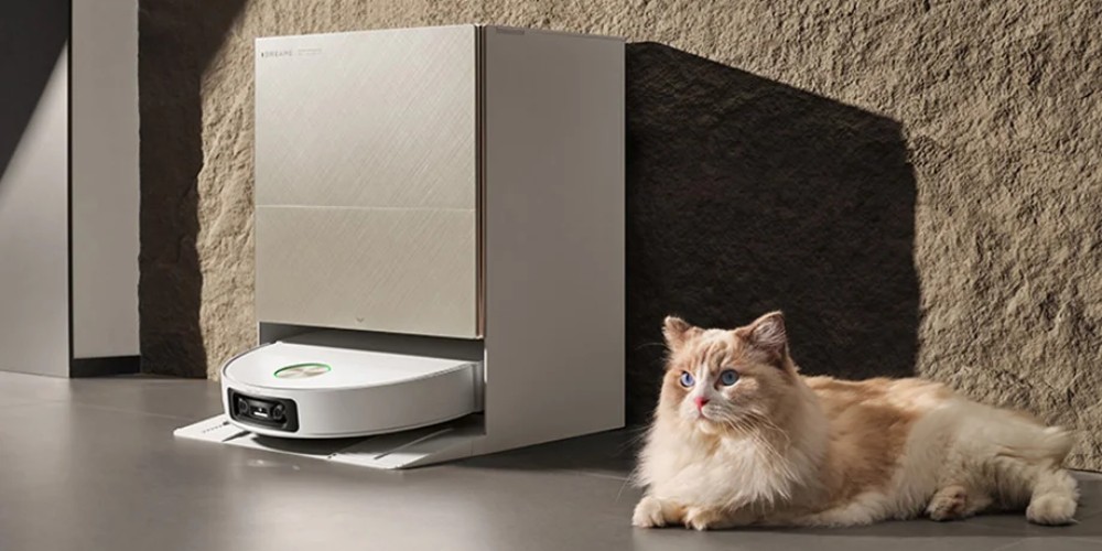 robot sprzątający Dreame X60 Ultra Complete ładuje się w stacji, obok leży kot