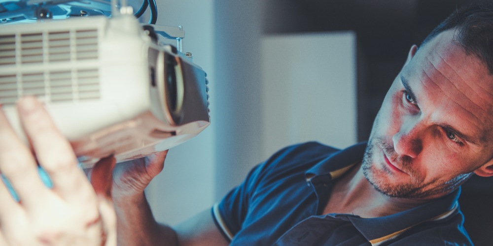 mężczyzna ustawia projektor multimedialny