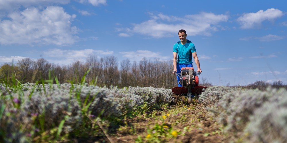 Mężczyzna z gleboryzarką przygotowujący pole do zasiewu
