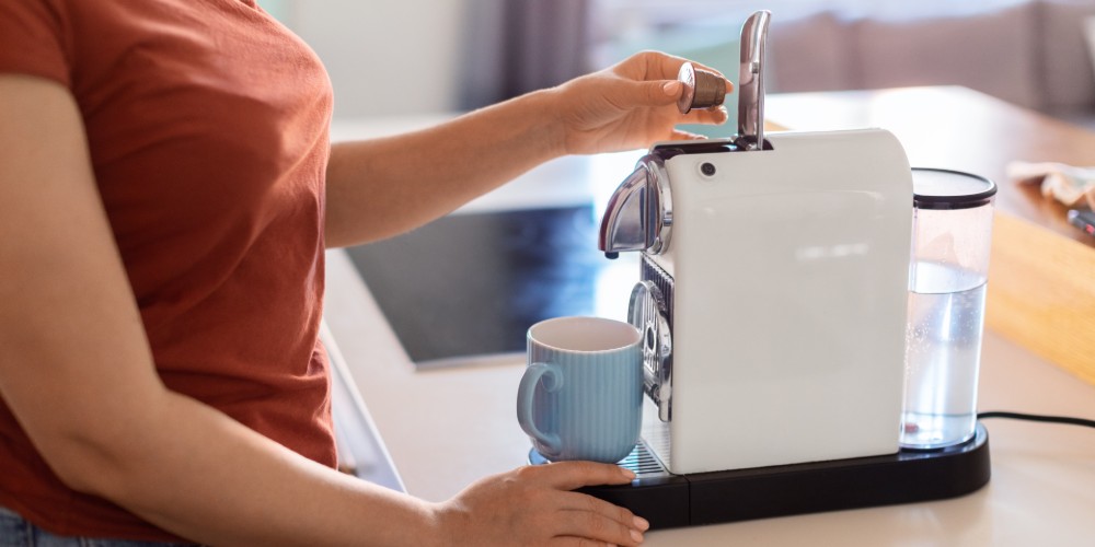 Kobieta parzy kawę w ekspresie kapsułkowym