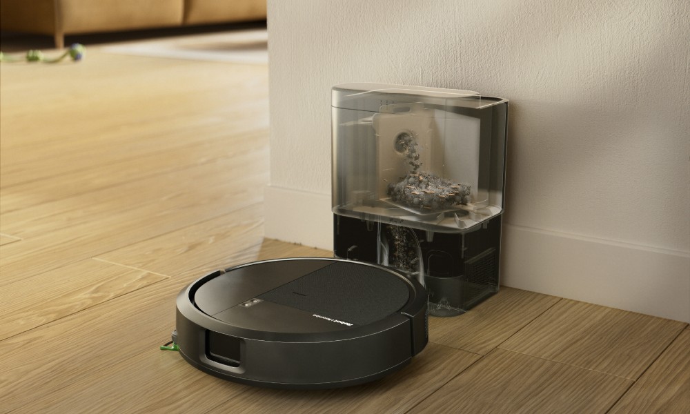 Czarny robot sprzątający iRobot Roomba 115 Combo ze stacją opróżniającą stoi przy ścianie