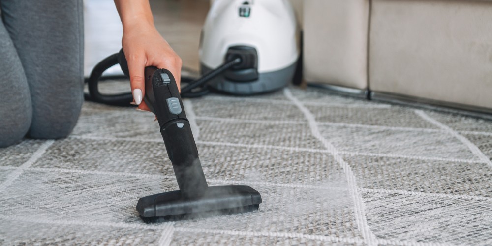 Kobieta piorąca dywan parą