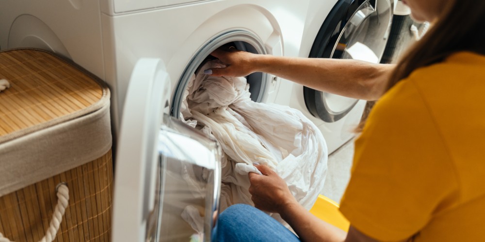 Kobieta wyciagajaca pranie z pralki