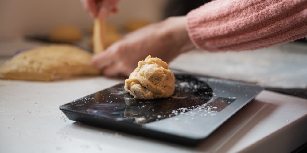 Kobieta ważąca ciasto na wadze elektronicznej
