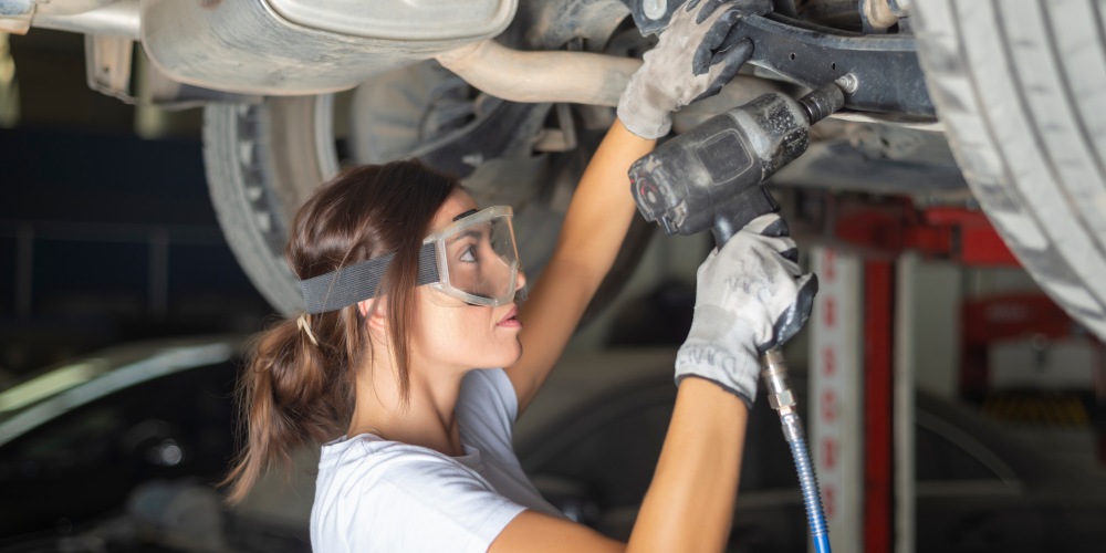 kobieta mechanik trzyma klucz udarowy pneumatyczny naprawiając samochód