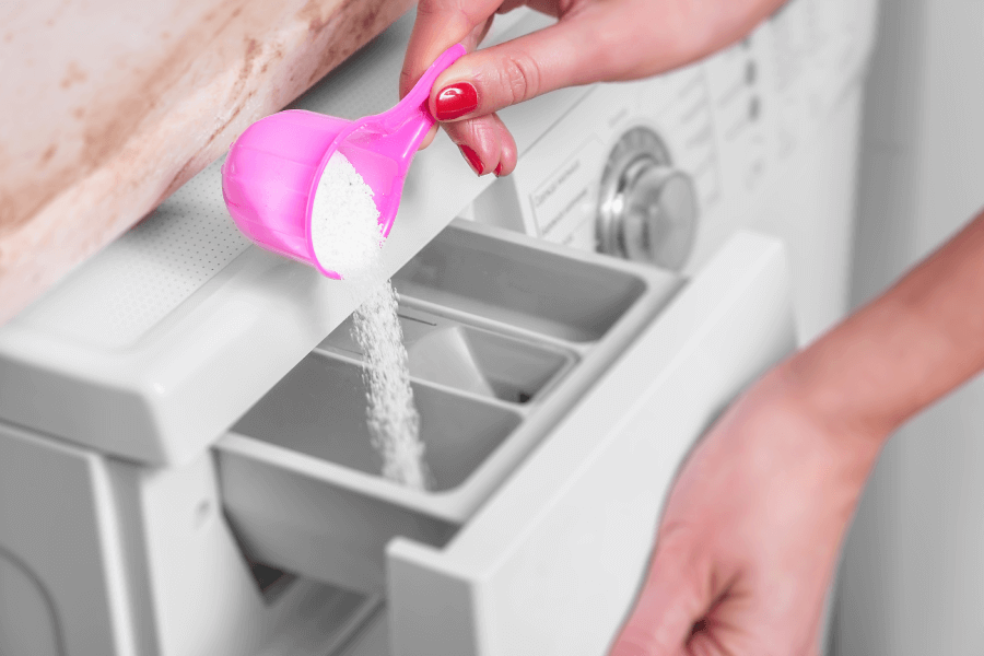 kobieta wsypuje proszek do szuflady pralki