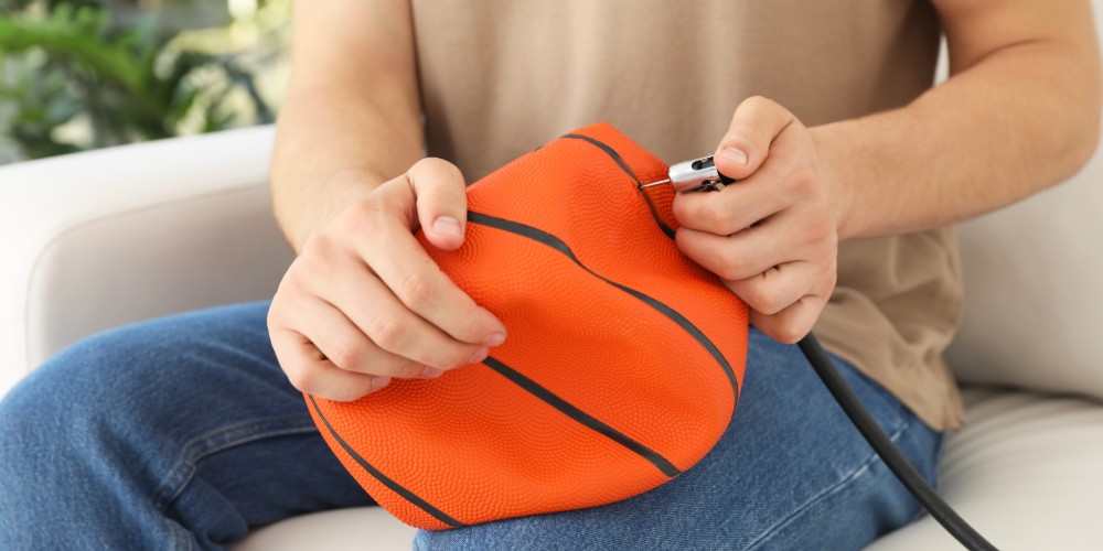 Mężczyzna pompujący piłkę do koszykówki