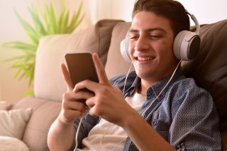Nastolatek słychający muzyki ze smartfona.