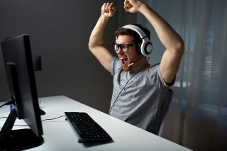 mężczyzna w słuchawkach na uszach, cieszący się przed monitorem komputera