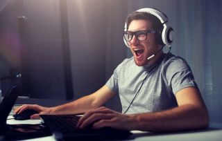 Mężczyzna ze słuchawkami na uszach, z dużym entuzjazmem grający w grę komputerową