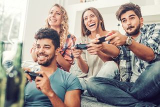 Czwórka przyjaciół w młodym wieku, grająca wspólnie na konsoli wideo
