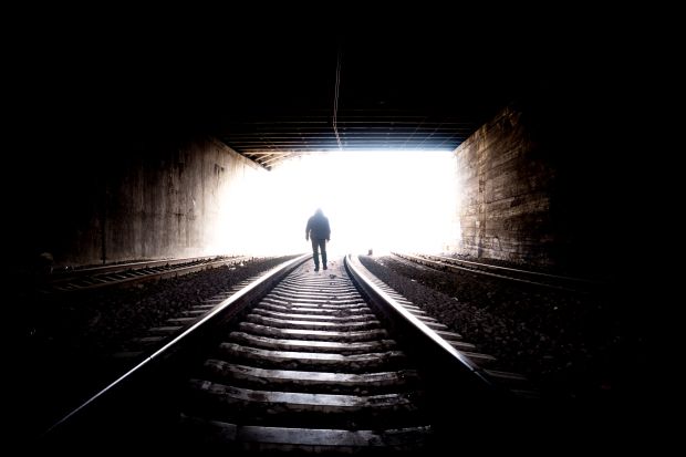 Mężczyzna stojący w ciemnym tunelu na torach kolejowych