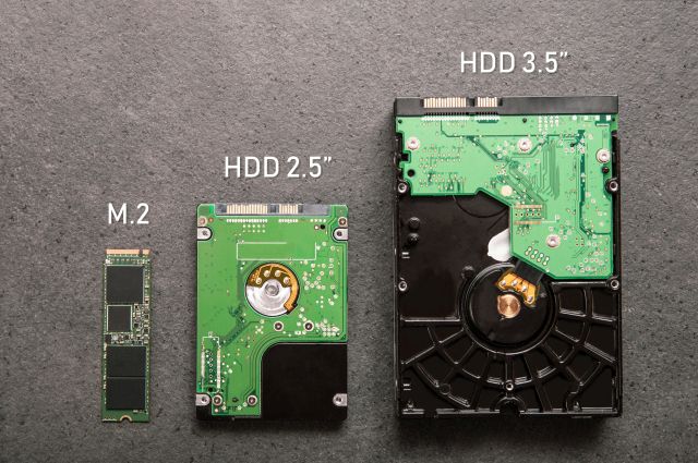Trzy dyski twarde leżące na kamiennej płycie – patrząc od prawej, największy rozmiarowo HDD, średni SDD i najmniejszy SSD M.2.