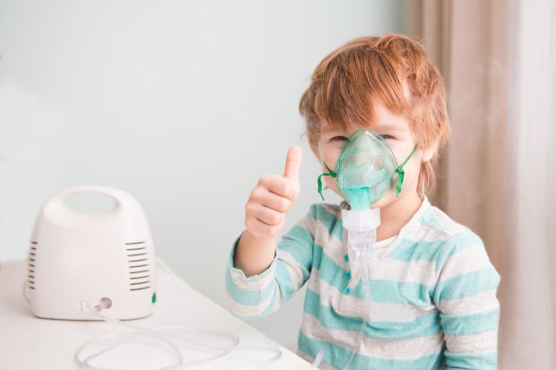 Radosny chłopiec wykonuje nebulizację w domu