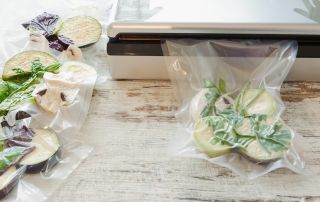  Surowe warzywa w plasterkach i grzyby pakowane próżniowo na drewnianym stole