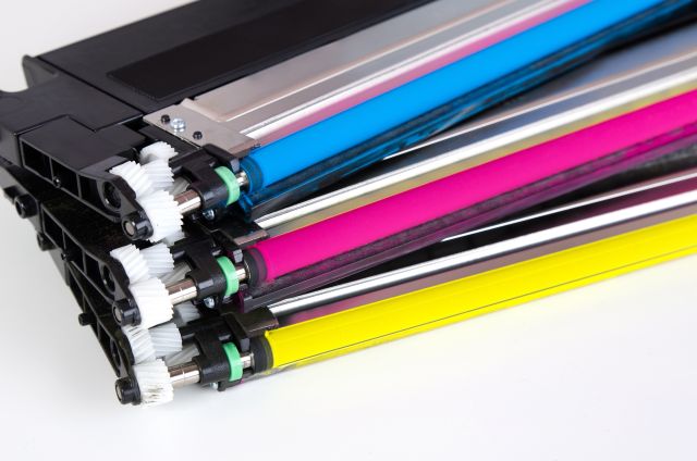 Tonery do drukarek laserowych w kolorze niebieskim, żółtym i różowym na białym tle