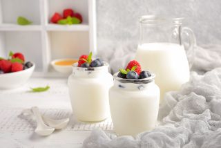 Dwa słoiczki udekorowane owocami i większy dzbanek z domowym jogurtem 