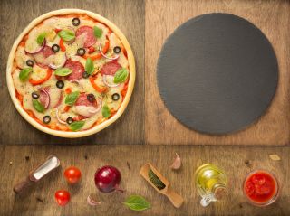 Pizza obok kamienia do pizzy, przypraw i dodatków do pizzy