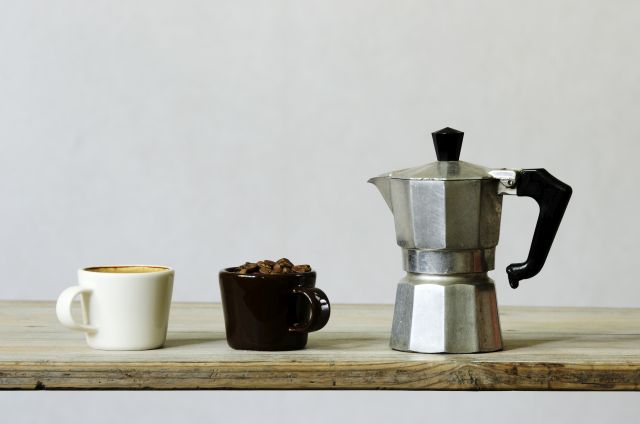 Kawiarka obok filiżanki z kawą i filiżanki z ziarnami kawy
