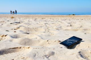 Zgubiony smartfon leżący w piasku na plaży